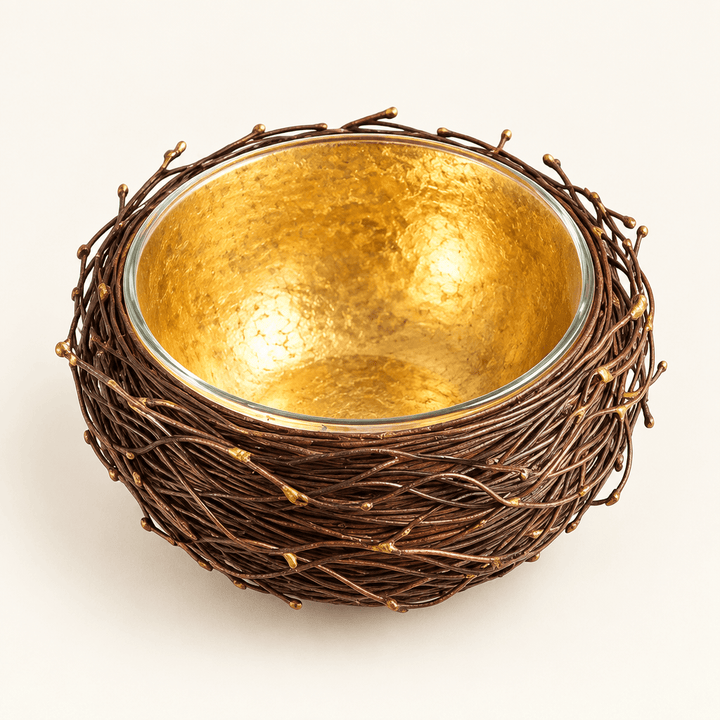 Metal nest-shaped bowl with a gold-leafed interior and glass liner on an ivory backdrop.