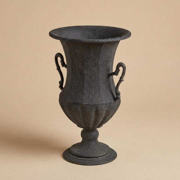 Valmont Scrolled Iron Amphora Urn in Black against a beige studio background, showing its scrolled handles, fluted bowl, and round pedestal.