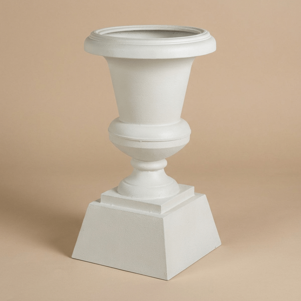 Hawthorne Aged Iron Urn Planter in Soft White against a beige studio background, showing its broad rim and stepped square base.