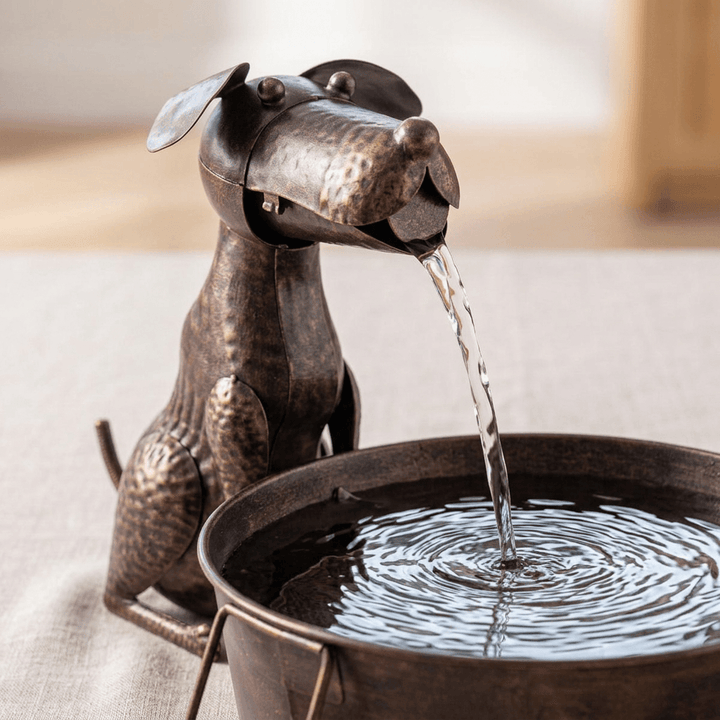Close view of the iron dog's floppy ears, textured bronze-toned finish, and water flowing into the basin.