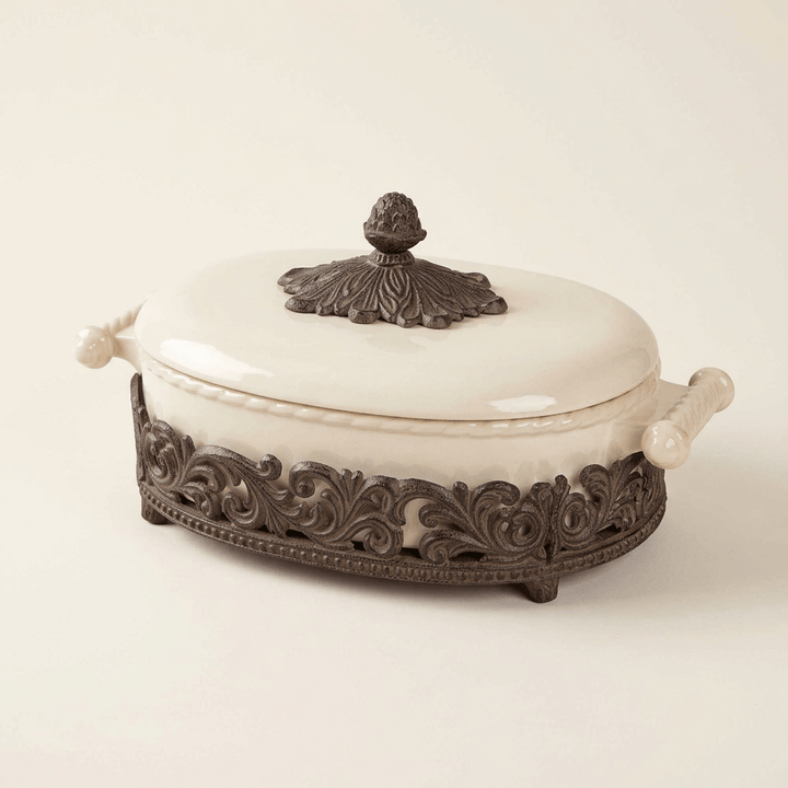 Bellavita cream stoneware lidded casserole dish with ornate dark metal cradle on a neutral studio background