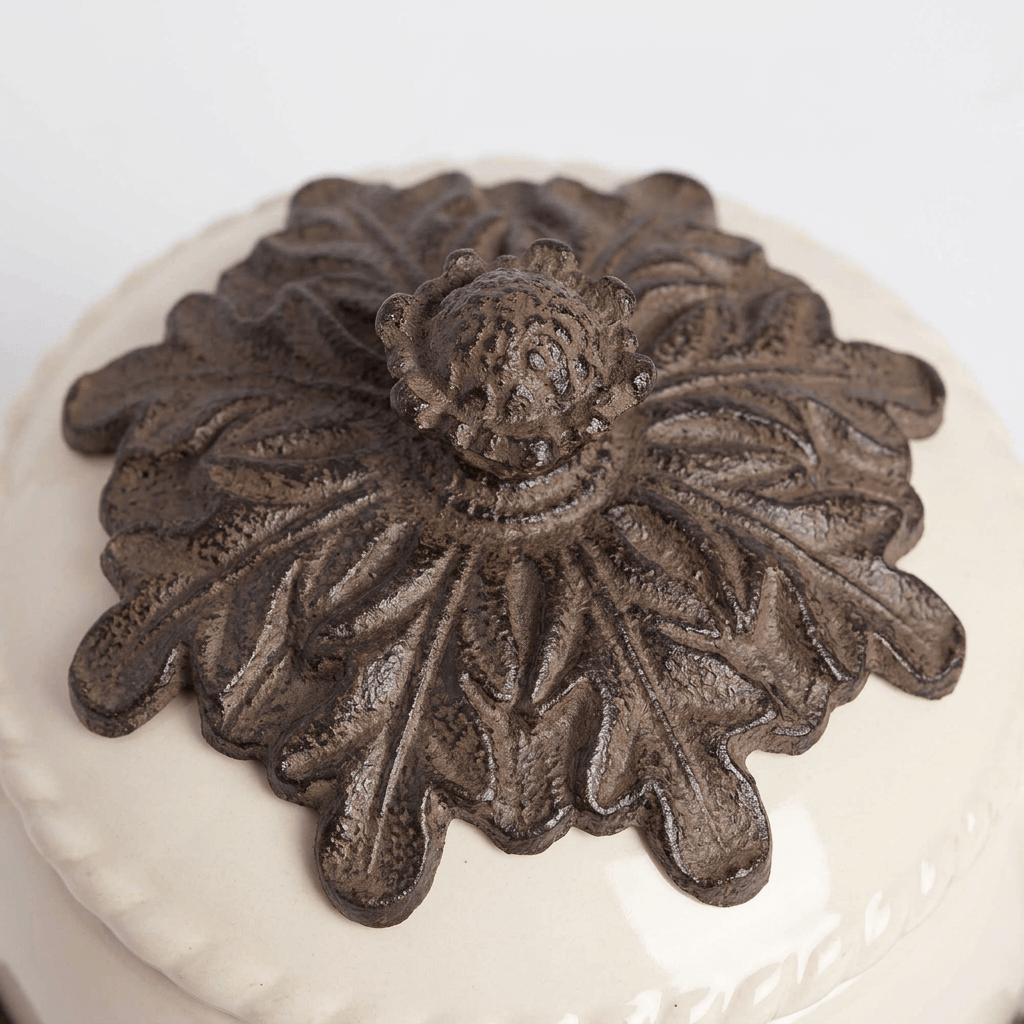 Close-up of dark metal acanthus leaves and ornamental finial on the cream teapot lid