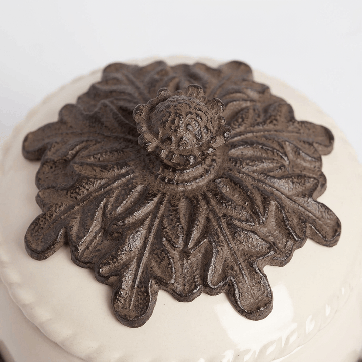 Close-up of dark metal acanthus leaves and ornamental finial on the cream teapot lid