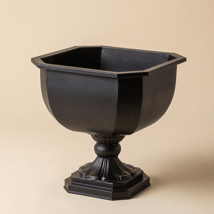 Empty Octavia black iron chalice planter showing its octagonal rim, faceted bowl, and fluted pedestal against a beige studio backdrop.