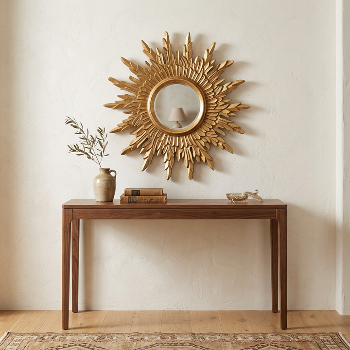 Celeste Gold Sunburst Wall Mirror styled above a walnut console in an ivory entryway.