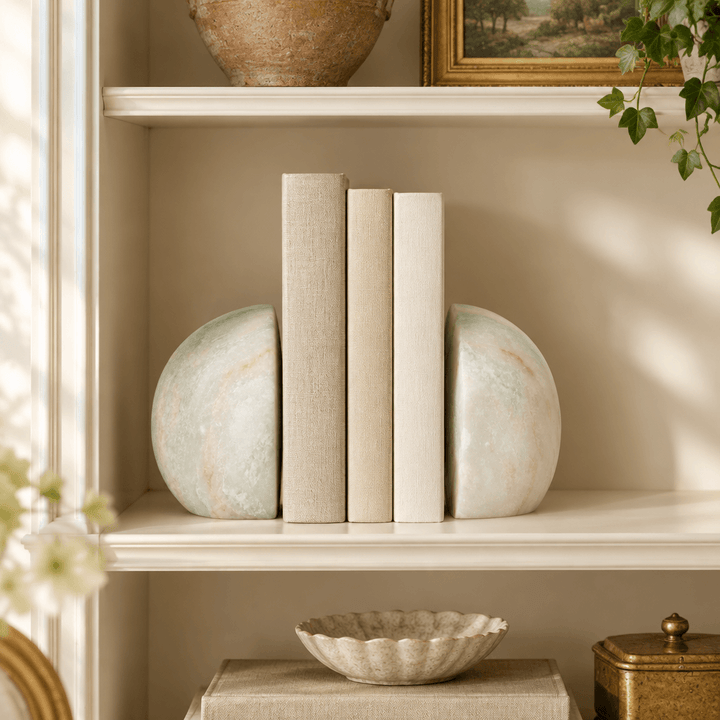 Green and white rounded marble bookend pair styled with books on a cream library shelf.