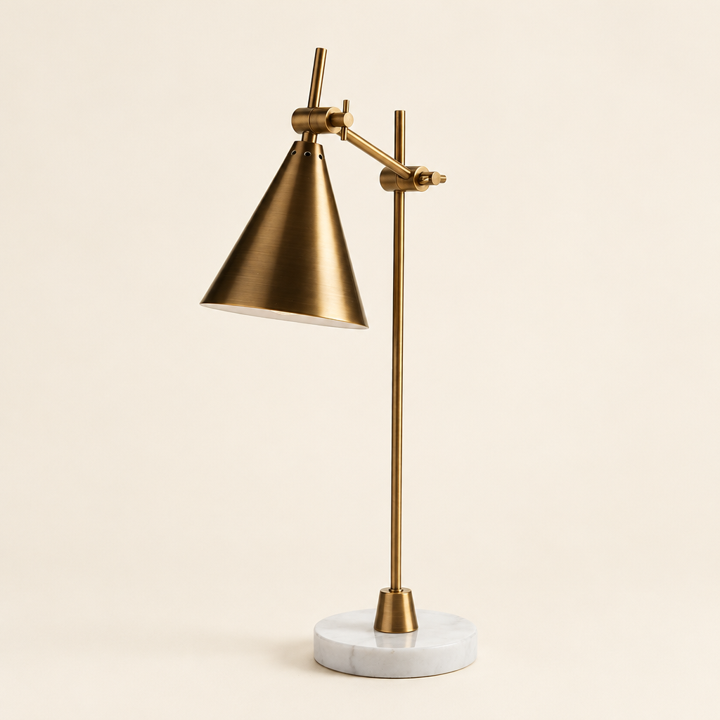 Brass-finish adjustable desk lamp with conical shade and round white marble base on an ivory background.