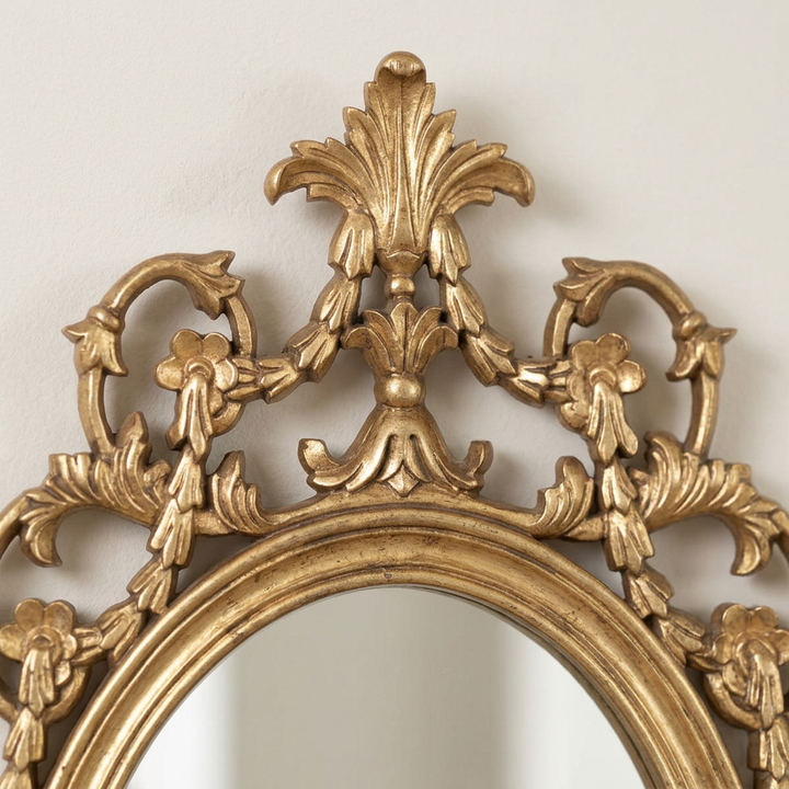 Close-up of the Antoinette Soft Gold Oval Wall Mirror showing carved foliate details, open scrollwork, and the layered gold oval frame.