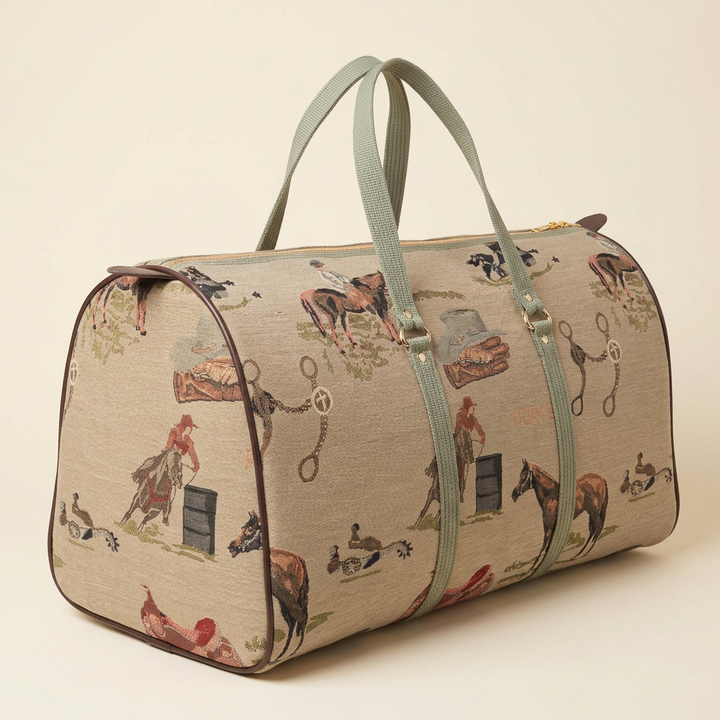 Western equestrian tapestry duffle with muted green handles and horse-and-rider motifs on an ivory studio background.