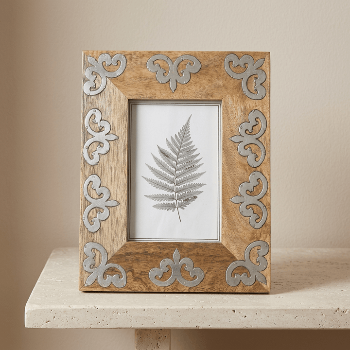Front view of the Belvedere mango wood photo frame with silver-tone scrolling motifs on a pale stone console.