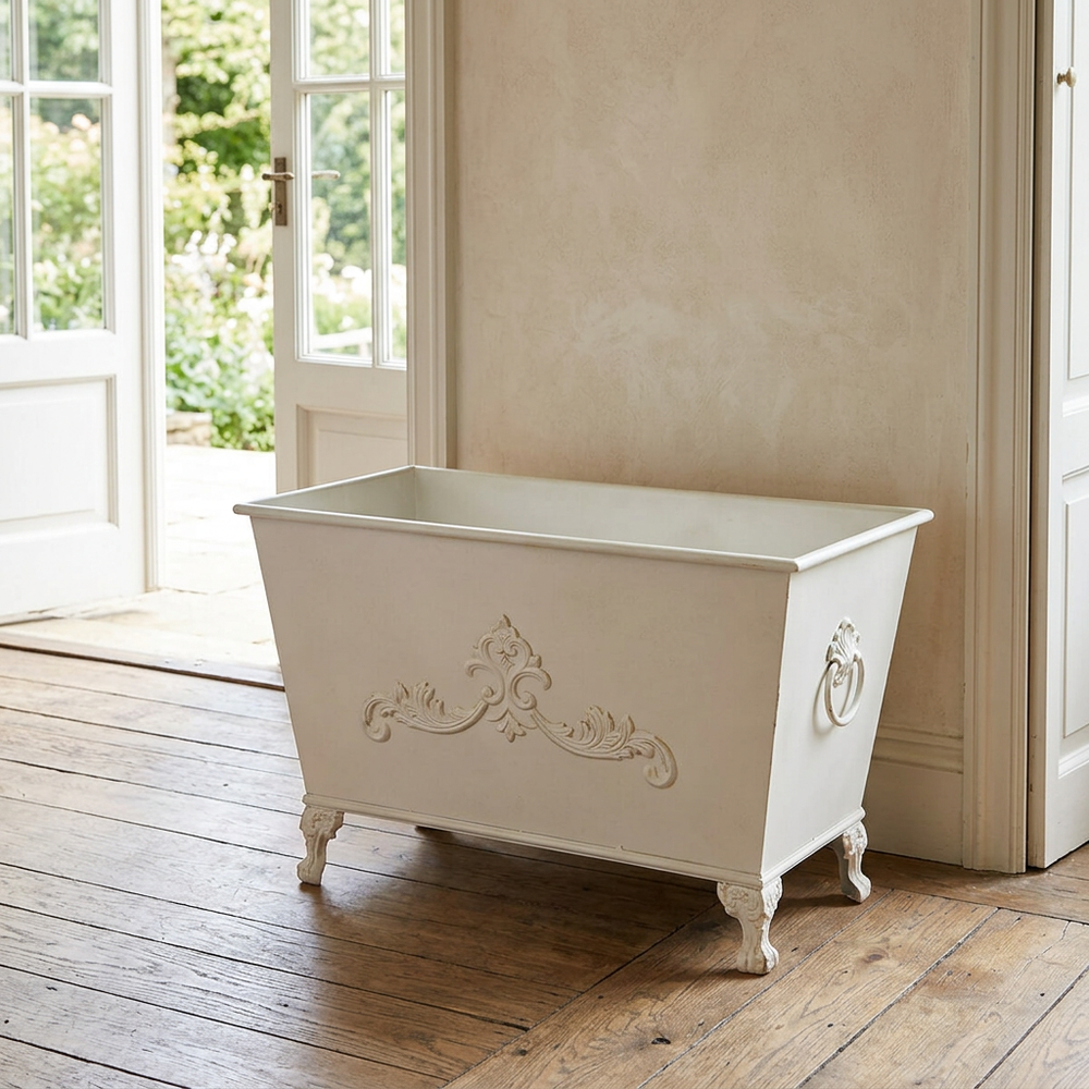 Aveline Scrollwork Metal Planter in Antiqued White with decorative scrollwork and side ring handle near French doors.