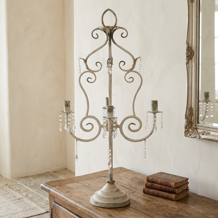 French Country Crystal Table Chandelier styled on a rustic wood sideboard beside antique books and an ornate mirror.