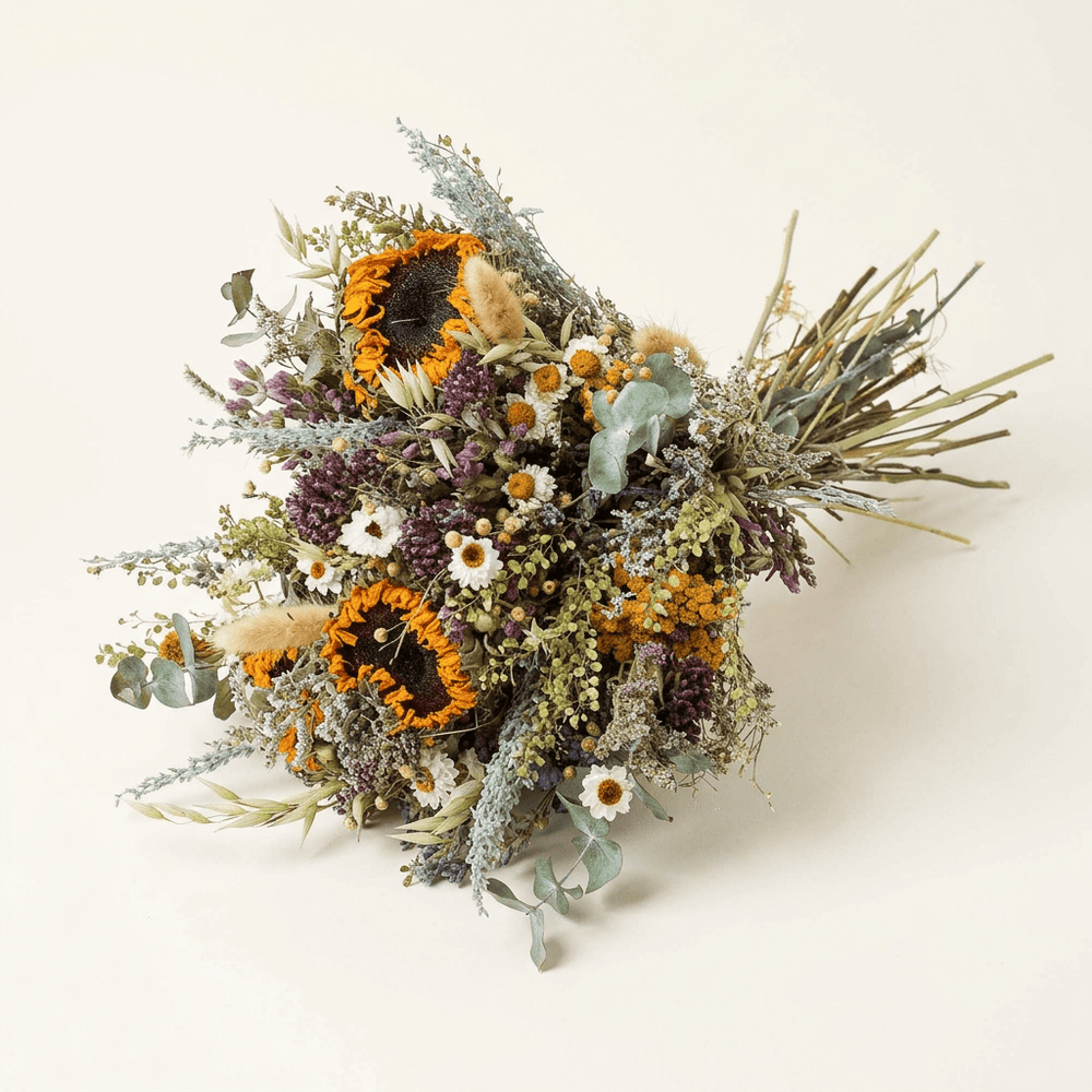 Dried sunflower and eucalyptus bouquet with white daisies and yarrow on a warm white studio background.