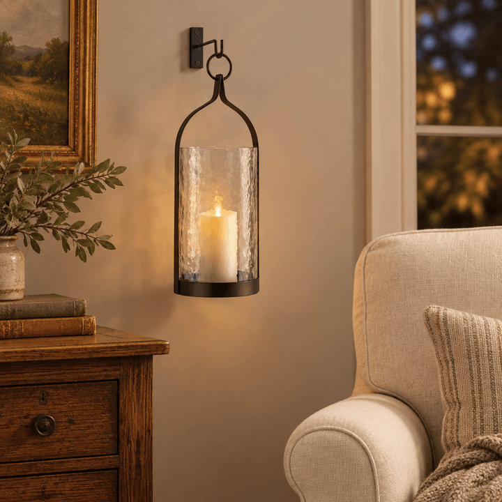 Hammered glass and iron lantern hanging beside a linen armchair with a glowing LED flameless candle