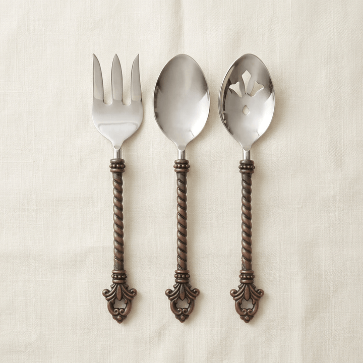 Bellavita three-piece serving set with stainless steel heads and twisted dark brass handles on ivory linen.