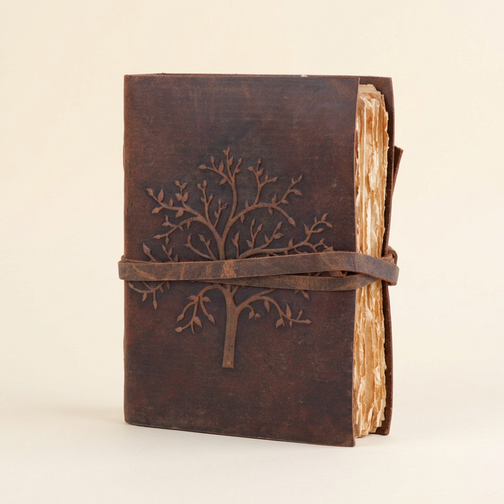 Brown Tree of Life embossed buffalo leather journal with wraparound strap on an ivory background