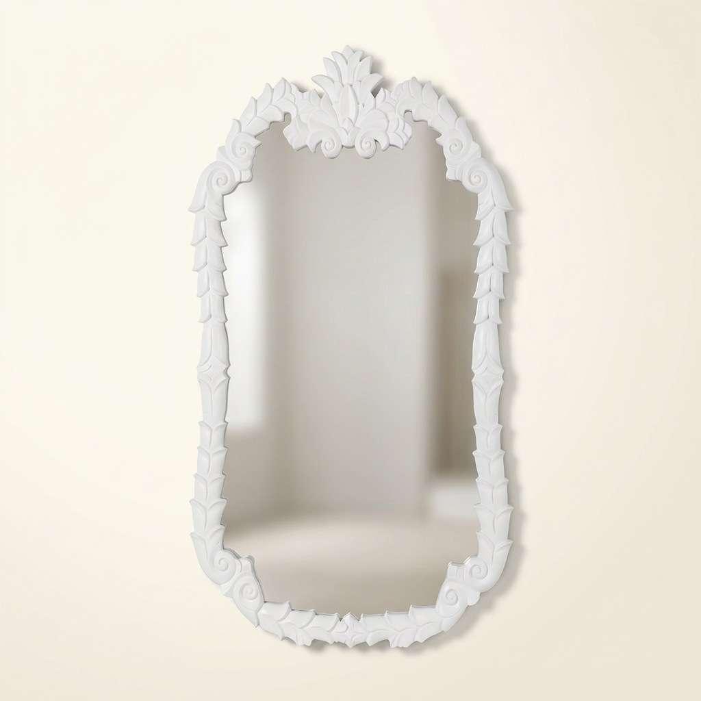White Colette carved wood wall mirror with leaf border and ornamental crest against an ivory studio background.