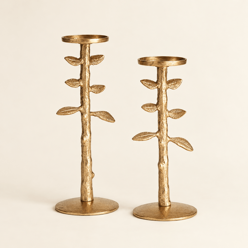 Two gold cast-aluminum candle stands showing sculpted leafy stems, round bases, and empty candle trays.