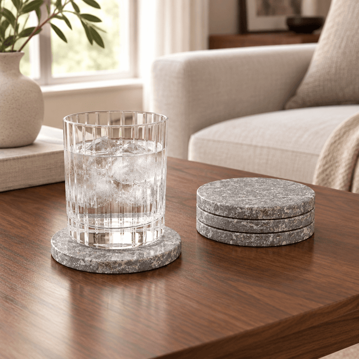 Round gray marble coasters styled with a drinking glass on a walnut coffee table.
