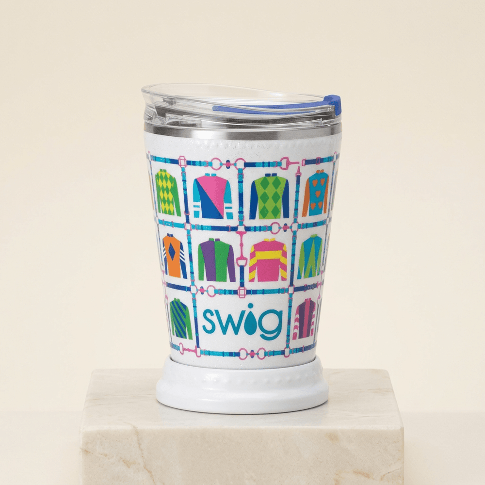 Glitter-white mint julep tumbler with colorful jockey silks, silver rim, and clear blue-slider lid on ivory stone.