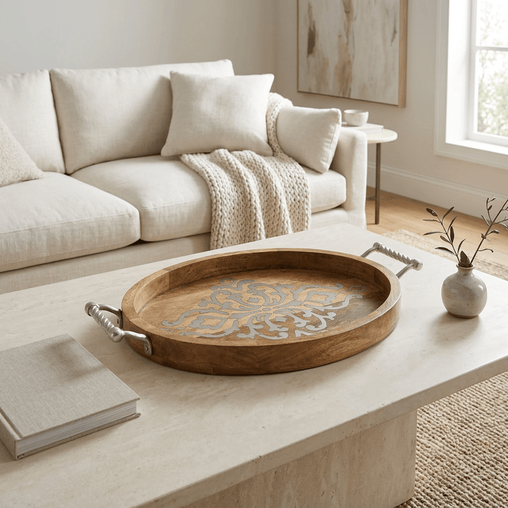 Belvedere oval serving tray with ornate metal inlay on a pale stone coffee table in a neutral living room.