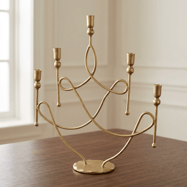 Five-arm antique gold iron scrollwork candelabra on a dark wood dining table.