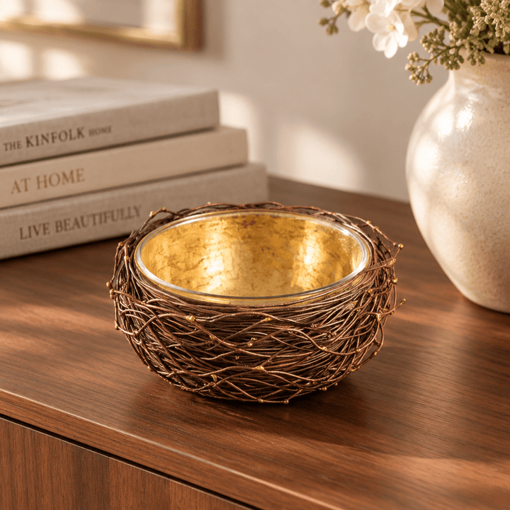 Gold-leafed metal nest bowl with glass liner styled on a walnut console beside books.