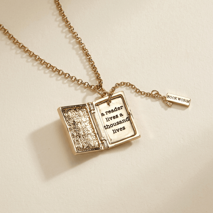 Open gold-tone book locket revealing a reader lives a thousand lives message and BOOK WORM bookmark charm.