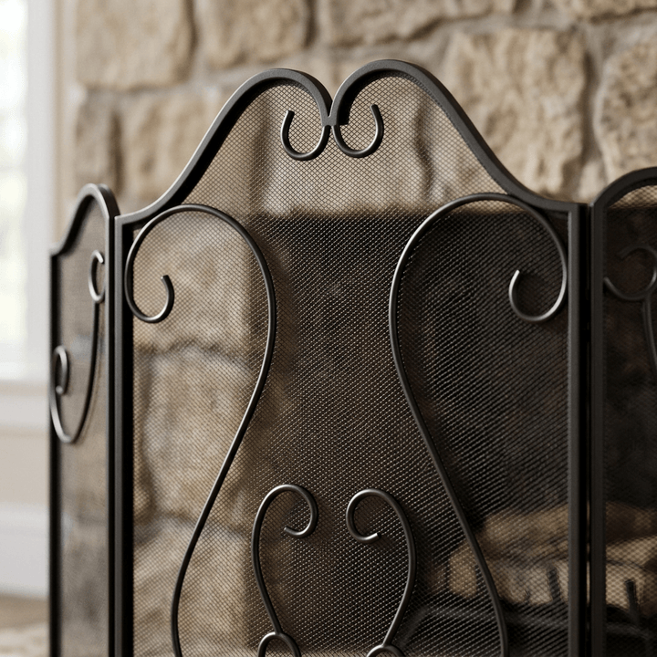 Close-up of the curved crest, decorative black scrollwork and fine mesh of the fireplace screen