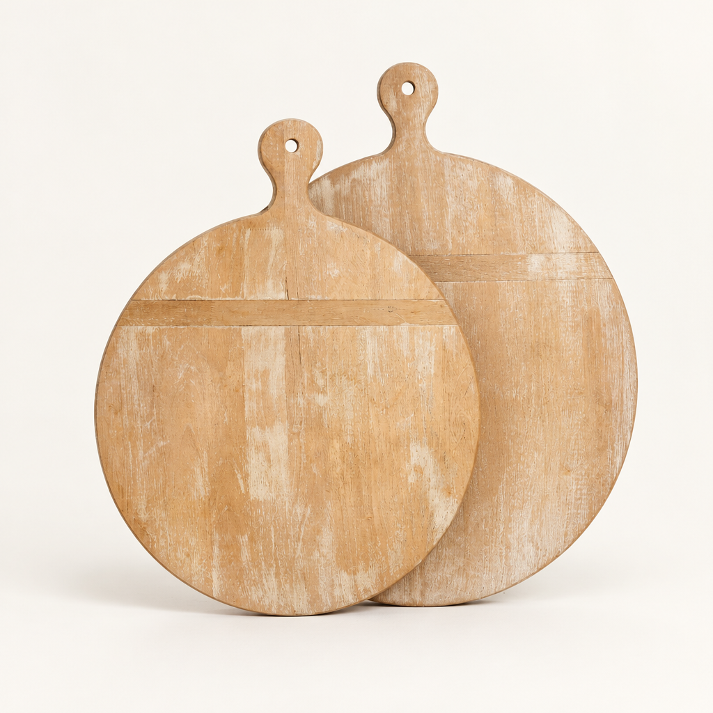 Two cream whitewashed round wooden boards with rounded handles on an ivory studio background.