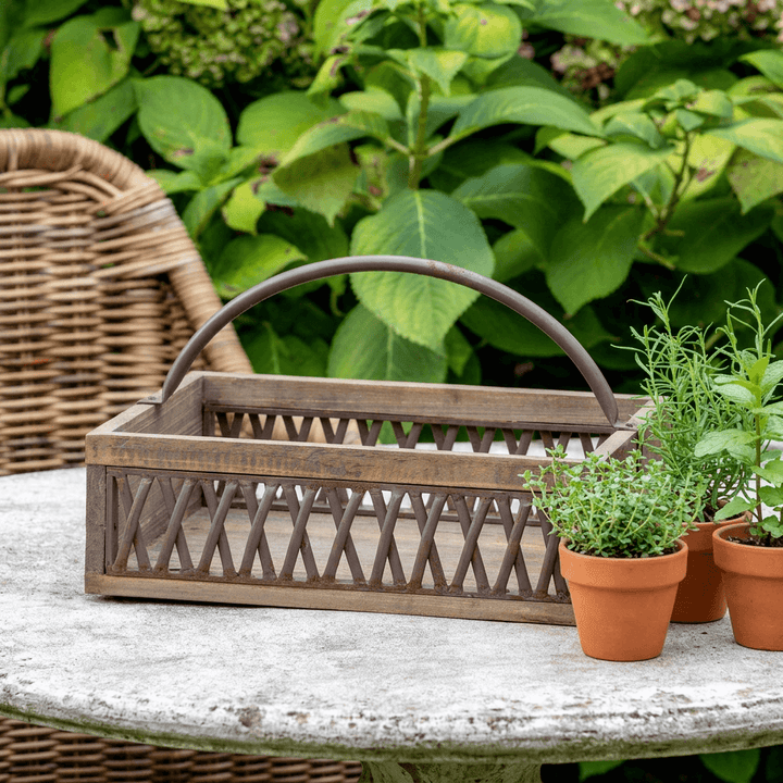 Bramley Garden Caddy, a weathered wood and iron lattice caddy with an arched iron handle, styled empty on a rustic farmhouse console table