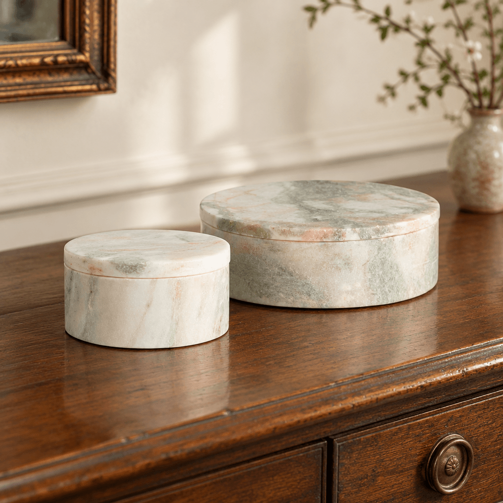 Green and white marble lidded boxes styled together on a walnut entry console.