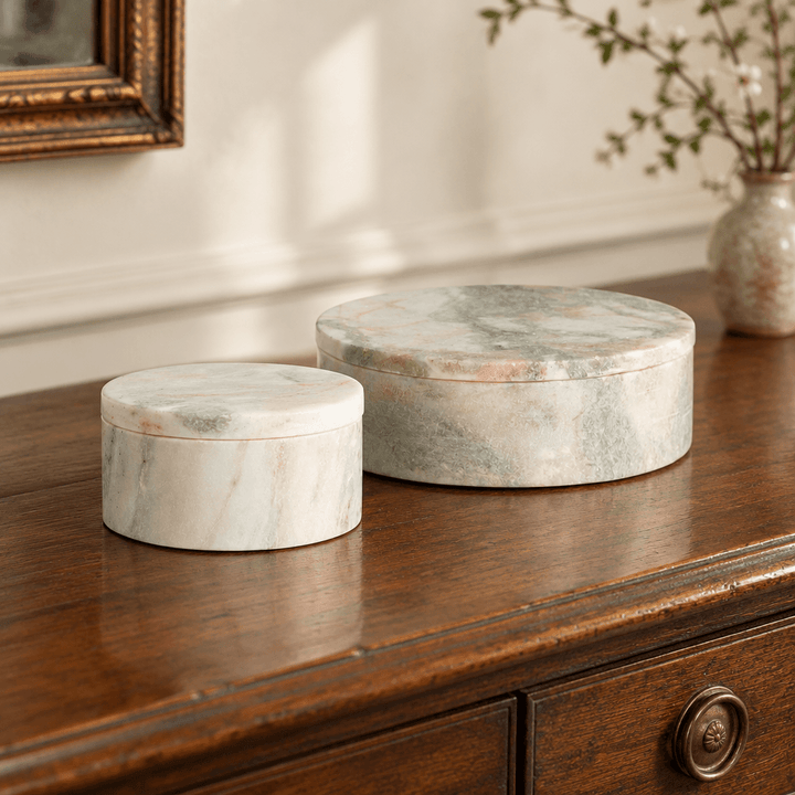 Green and white marble lidded boxes styled together on a walnut entry console.