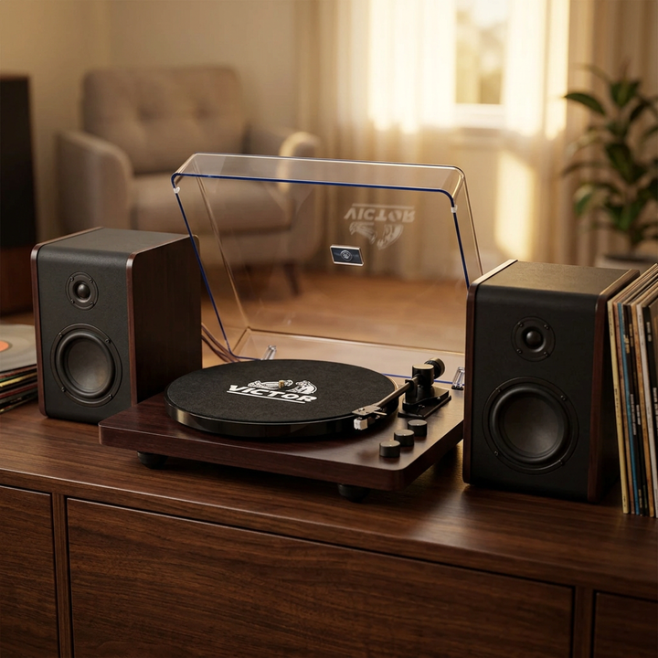 Victor Lincoln turntable with open clear dust cover and matching detached speakers on a dark wood console in a warmly lit music room.