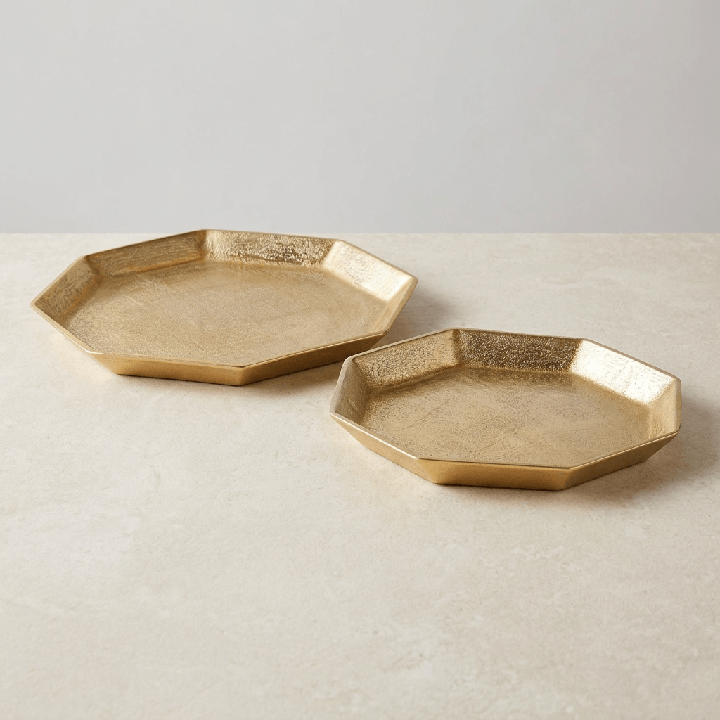 Two gold octagonal cast aluminum serving trays with shallow angled rims on a neutral studio surface.