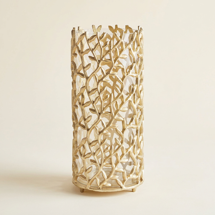Gold vine hurricane candle holder with clear glass insert on an ivory studio background.