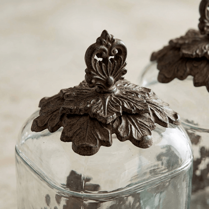 Close-up of the Bellavita canister's domed glass lid with dark metal leaf overlay and ornate finial