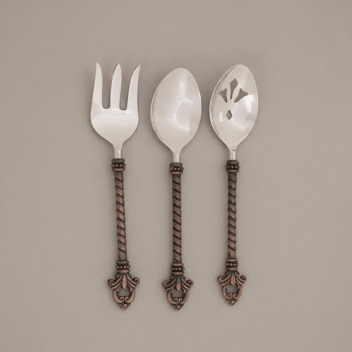 Full view of Bellavita serving fork and two serving spoons on a muted taupe background.