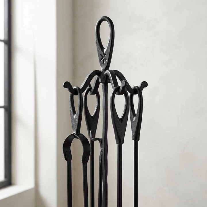 Close detail of oval loop handles and the upper stand of a black wrought iron fireplace tool set