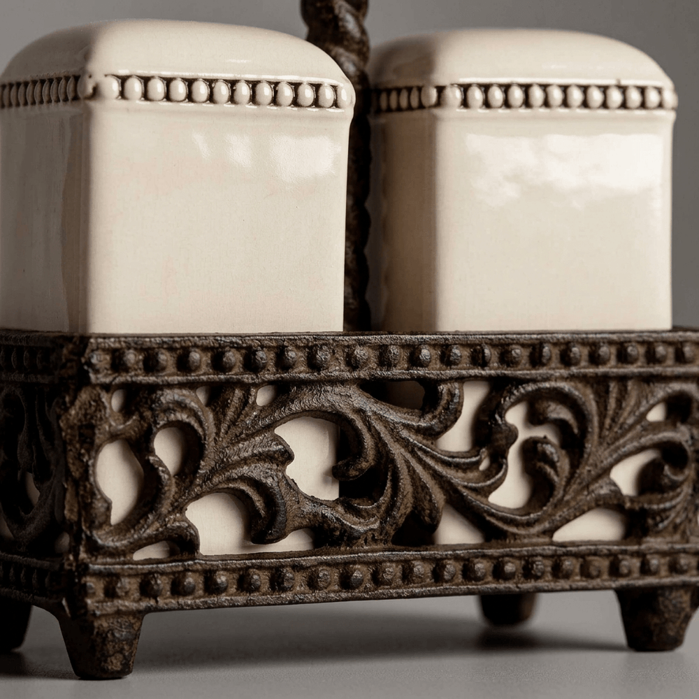 Close-up of Bellavita cream ceramic shakers, beaded borders, and brown acanthus-leaf metalwork.
