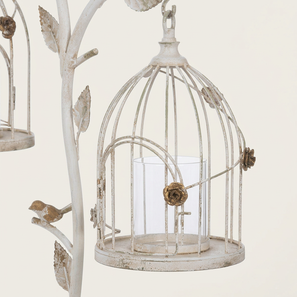 Close-up of a domed white iron lantern showing gold rose details, an arched door, and a clear glass candle insert.