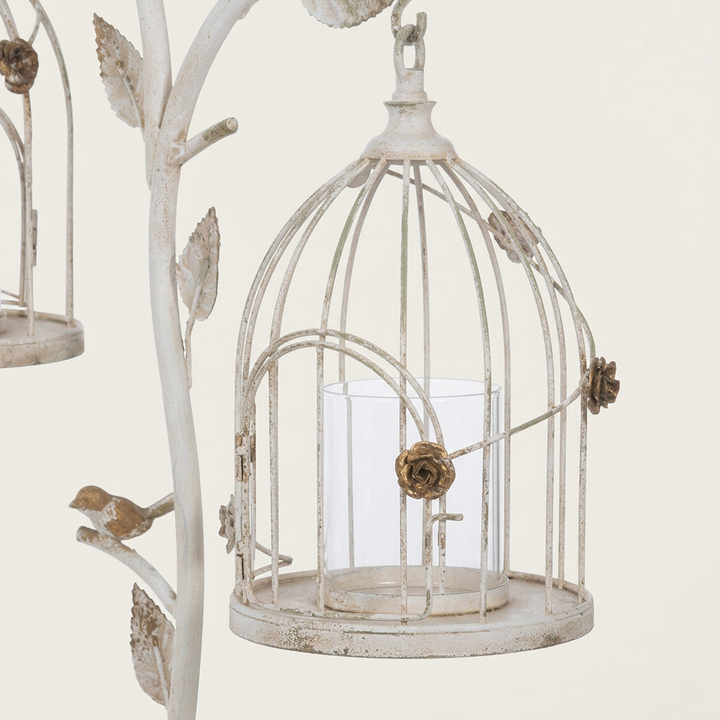 Close-up of a domed white iron lantern showing gold rose details, an arched door, and a clear glass candle insert.