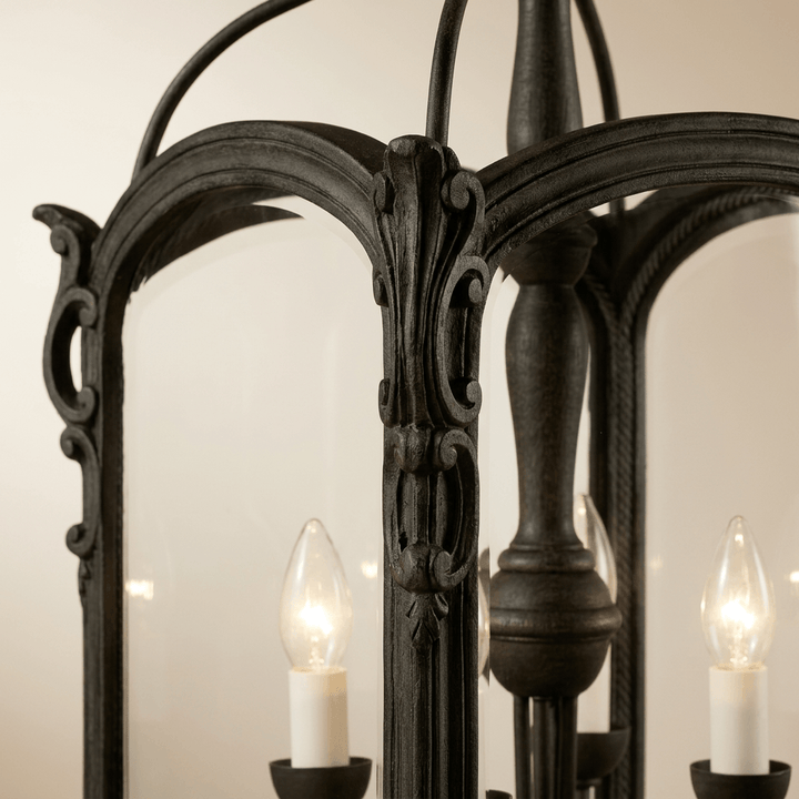 Close-up of the Bellamora lantern chandelier's antique black carved wood frame and candle-style lights.