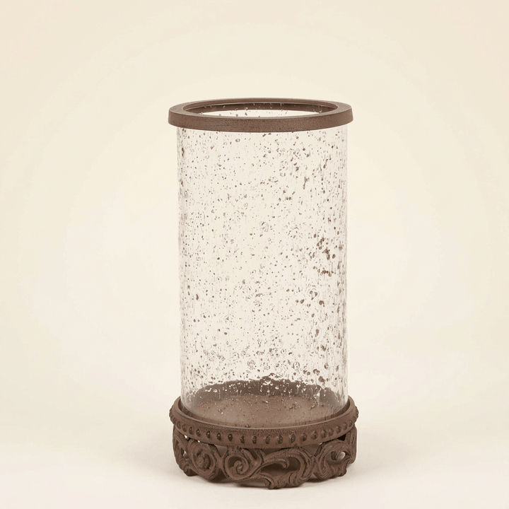 Smaller Bellavita Glass Hurricane Candle Holder with textured glass and brown acanthus base against an ivory studio background.