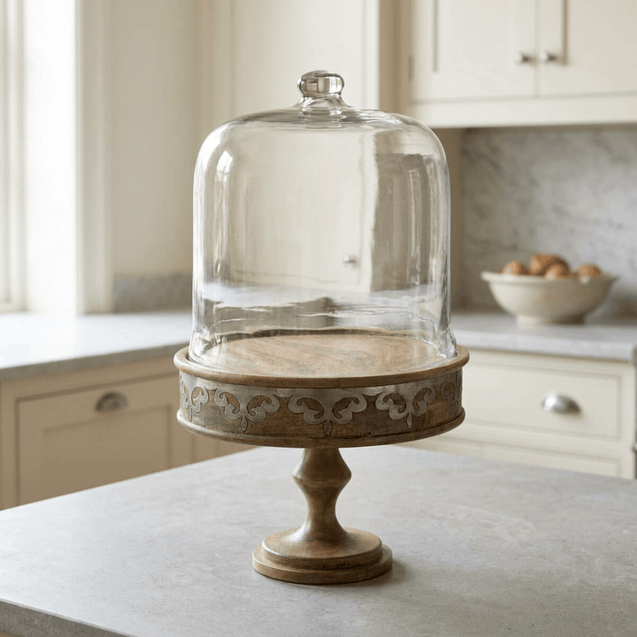 Belvedere Cake Pedestal with Glass Dome on a pale stone island in a cream kitchen.