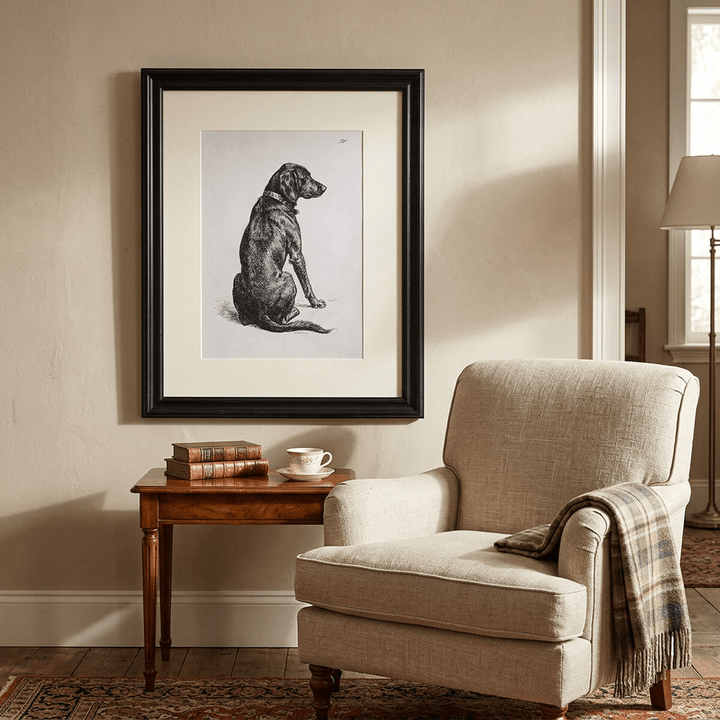 Devoted Heart Framed Dog Portrait displayed beside a linen reading chair and a table with books.