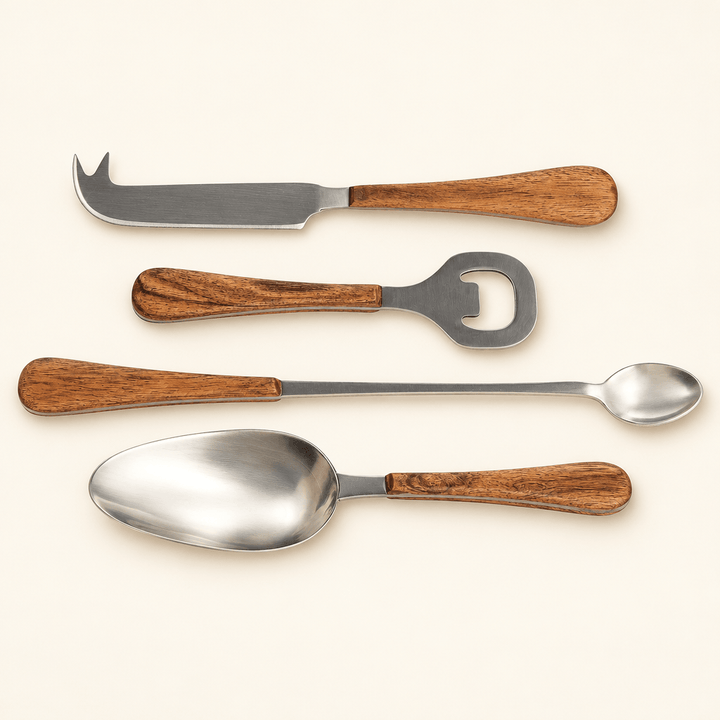 Four stainless steel cocktail accessories with carved acacia wood handles on an ivory background.