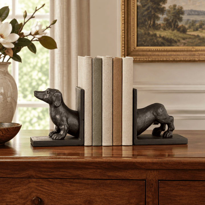 Black bronze split dachshund bookends styled with books on a walnut console.