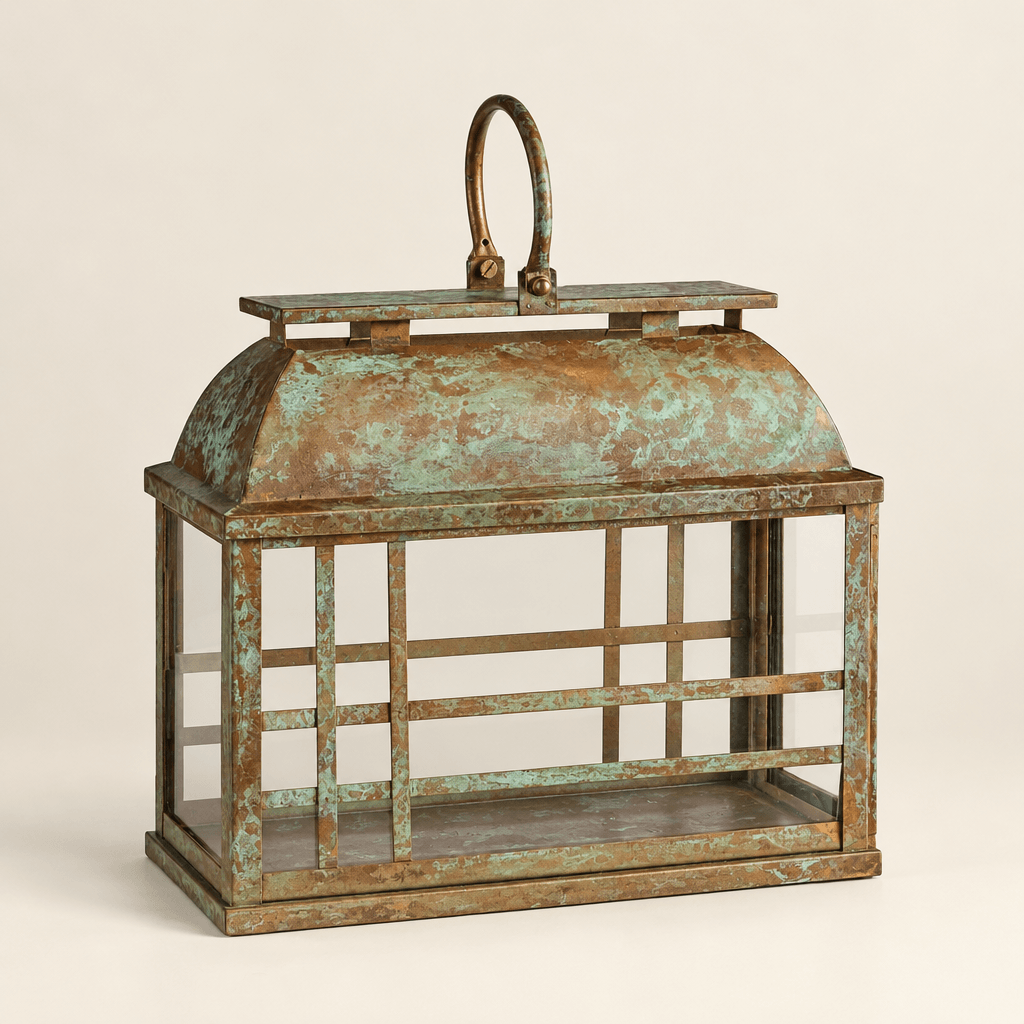 Empty weathered iron and glass lantern showing its curved roof, oval handle, and gold-and-green patina.