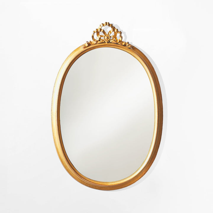 Gold-framed mirror with decorative top on a white background